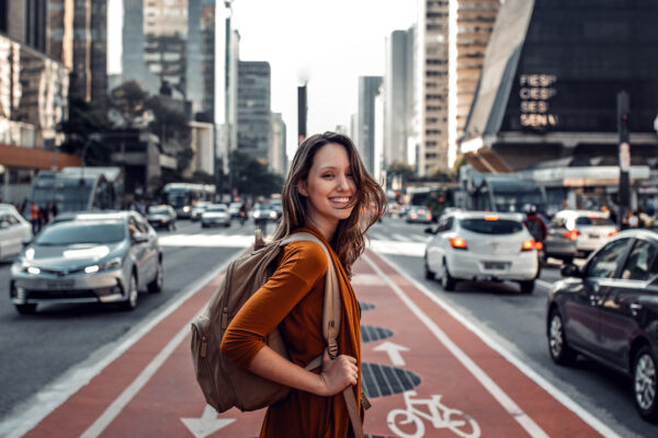 Woman standing in cross walk of busy street, while looking back and smiling