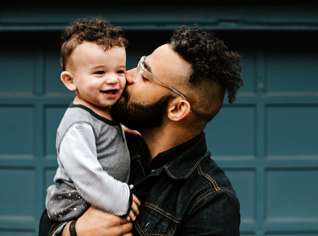 Young father kissing toddler son on cheek