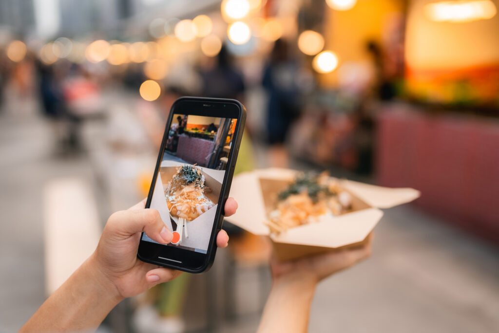 woman's hand taking photos of food at a food market.