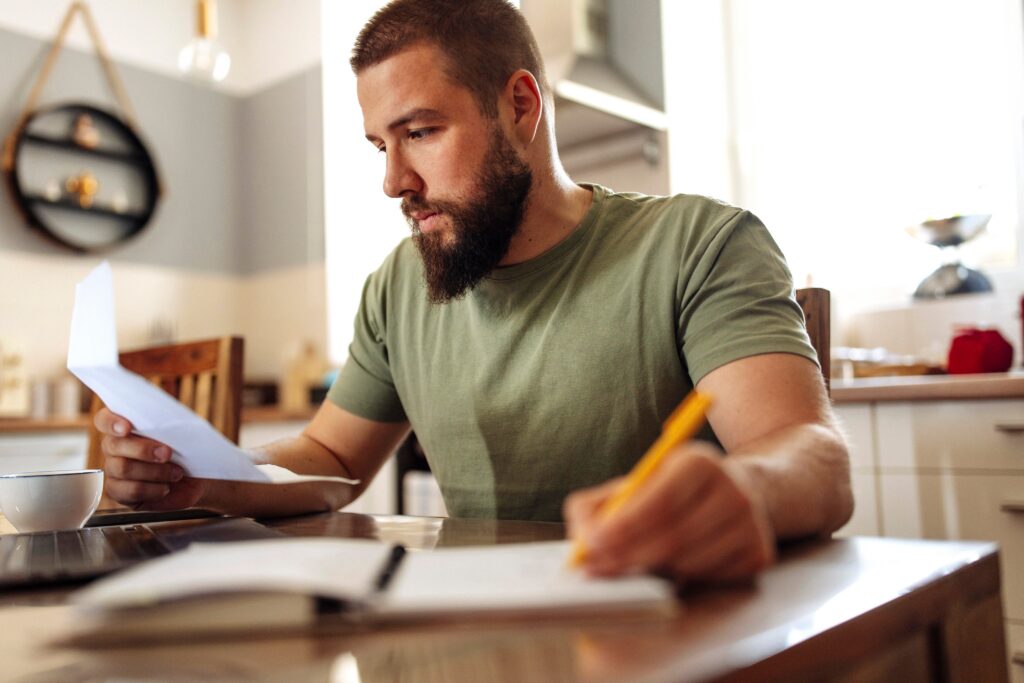 Young adult male with a beard working on finances at home.