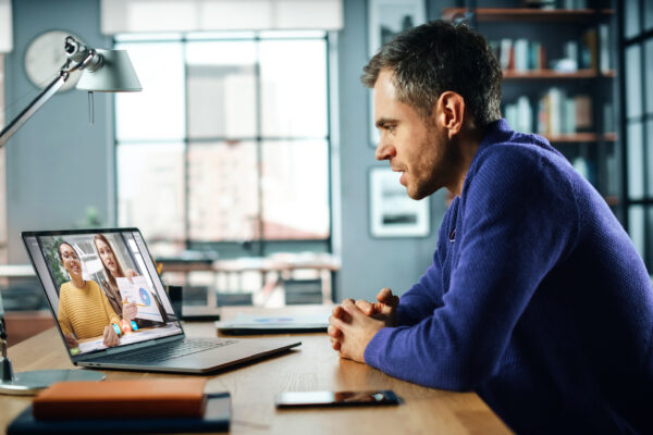 Man sitting at home office on laptop while meeting with financial coach on video call