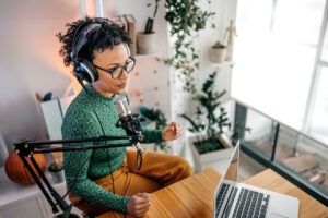 Woman wearing headphones while recording a podcast in home office