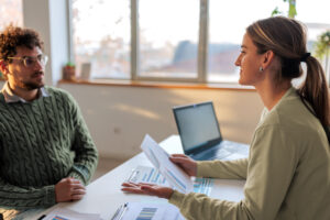 Male entrepreneur with glasses speaking with financial professional at her office