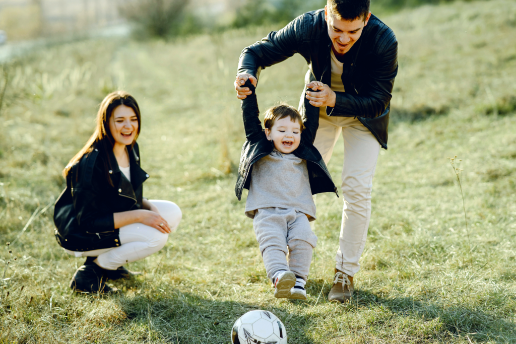 happy family playing outside, father lifting child off the ground