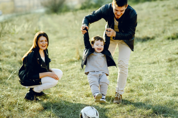happy family playing outside, father lifting child off the ground